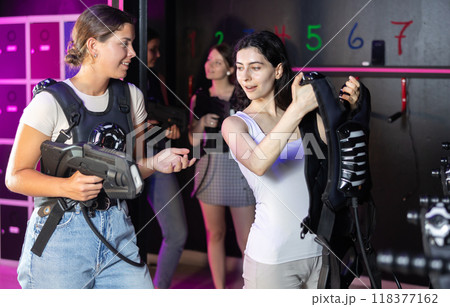 Young women choose protective equipment and uniforms before playing laser tag 118377162