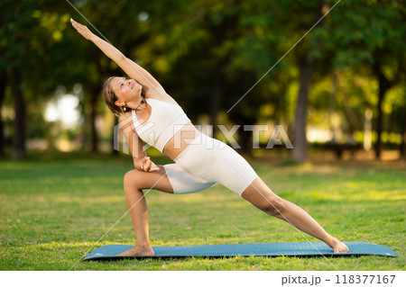 Girl performing Extended Side Angle Pose during yoga practice outdoors Girl performing Extended Side Angle Pose during yoga practice outdoors 118377167