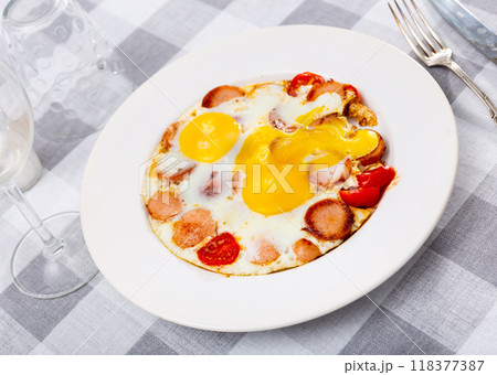 Fried eggs with tomato served with sausage 118377387