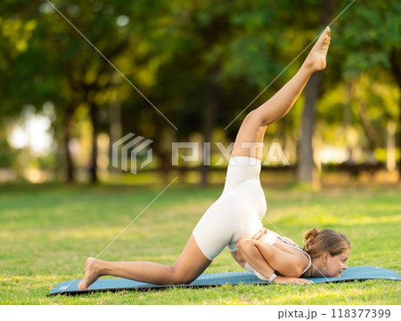 Young woman practicing yoga on green glade in summer park 118377399