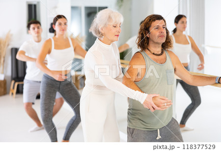Female ballet teacher showing moves in front of group of different aged dancers in dancing studio 118377529