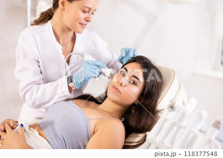 Young brunette undergoing high frequency ultrasound facial treatment 118377548
