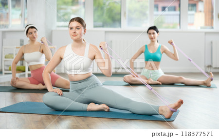 Young girls doing arm workout with band sitting leg extended 118377571