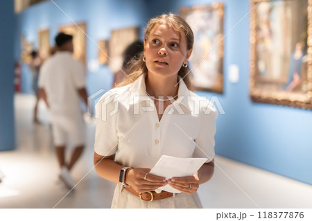 Portrait of young attractive woman holding an information booklet during a visit to fine arts museum 118377876
