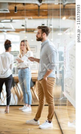 A man stands in front of a whiteboard with a group of people 118378093