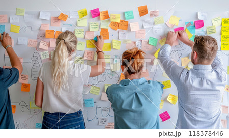 A group of people are writing on a whiteboard with colorful sticky notes 118378446