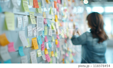 A woman is writing on a whiteboard with colorful sticky notes A woman is writing on a whiteboard with colorful sticky notes 118378454