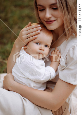 A woman is sitting on the grass with a baby in her arms 118381377