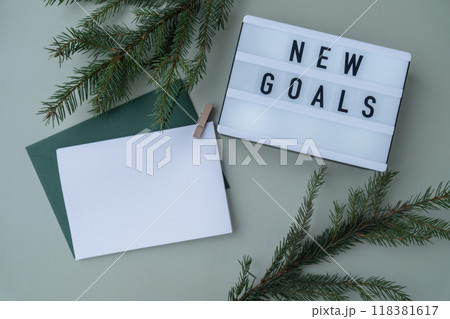 NEW GOALS text on Lightbox on green background with Christmas decor and copy space template mock up white envelope. New year aims resolutions. Planning and setting goals NEW GOALS text on Lightbox on green background with Christmas decor and copy space template mock up white envelope. New year aims resolutions. Planning and setting goals 118381617