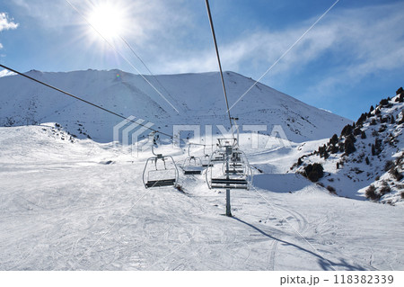 Chunkurchak ski resort in Kyrgyzstan. Empty ski lift seats. Mountain slope at sunny winter day Chunkurchak ski resort in Kyrgyzstan. Empty ski lift seats. Mountain slope at sunny winter day 118382339