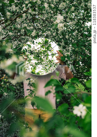 Creative male portrait with mirror in blooming apples spring garden Creative male portrait with mirror in blooming apples spring garden 118383537