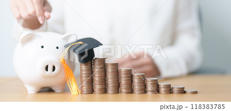Money saving for Education, Scholarship, Student loan and debt and study future plan concept. Coins stack growing up with piggy and graduation hat on table Money saving for Education, Scholarship, Student loan and debt and study future plan concept. Coins stack growing up with piggy and graduation hat on table 118383785