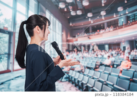 ホールで司会をする若い女性 118384184