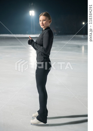 Beautiful young woman ice skating and performing short program 118384291