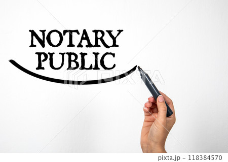 NOTARY PUBLIC. Hand holding black marker and writing on white background NOTARY PUBLIC. Hand holding black marker and writing on white background 118384570