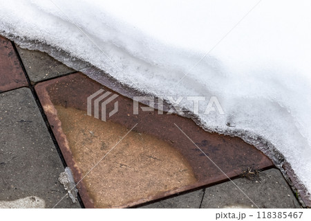 Snow is melting on the footpath 118385467