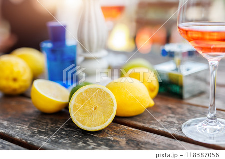 Pile of many bright ripe italian yellow lemons arranged on rustic  wooden table wine glasses and decorative stand at rural countryside terrace patio. Refreshing outdoor decoration dining atmosphere 118387056
