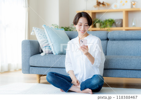 部屋でスマホを操作するミドル女性 118388467