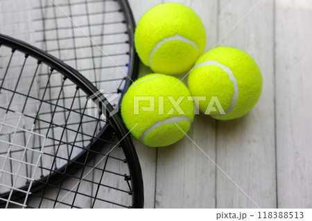 Three yellow tennis balls are lying on a white tree background in close-up, rackets are lying next to them. High quality photo 118388513