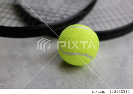 In the foreground lies a yellow tennis ball, behind it are tennis rackets on a gray background. Concept of competitions, sports. High quality photo 118388516