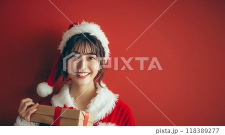 クリスマスプレゼントの箱を持ってサンタクロースの衣装を着た女性 118389277