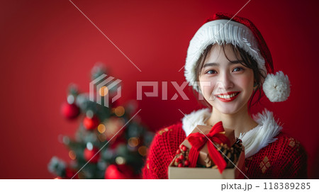 クリスマスプレゼントの箱を持ってサンタクロースの衣装を着た女性 118389285