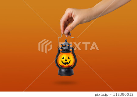 Halloween pumpkin lamp in a woman's hand. Halloween autumn concept. On orange background 118390012