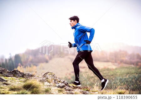 Male runner jogging in nature on dirt running trail. Morning running training for young man. Male runner jogging in nature on dirt running trail. Morning running training for young man. 118390655