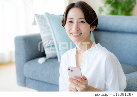 部屋でスマホを操作するミドル女性 118391297