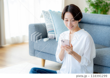 部屋でスマホを操作するミドル女性 部屋でスマホを操作するミドル女性 118391299