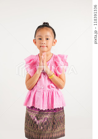 Portrait of Thailand kid girl smiling traditional Thai dress costume posing to pay respect in studio shot isolated white background, Happy kindergarten child sawasdee symbol or welcome 118391336