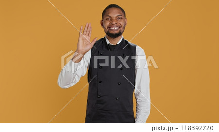 Skilled waiter waving and greeting clients at five star restaurant, working in hospitality industry and catering. Employee server welcoming customers to eat, professionalism. Camera B. Skilled waiter waving and greeting clients at five star restaurant, working in hospitality industry and catering. Employee server welcoming customers to eat, professionalism. Camera B. 118392720