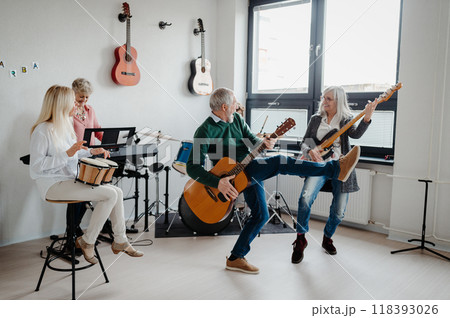 Group of seniors meeting to play musical instruments together in band, having fun. Therapeutic effect of music for elderly people. Group of seniors meeting to play musical instruments together in band, having fun. Therapeutic effect of music for elderly people. 118393026