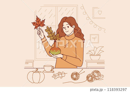 Woman collects bouquet of autumn leaves and places them in vase to decorate home on thanksgiving eve 118393297