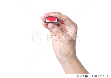 A woman's hand holds a mochi candy, shows the size and berry red filling on white background isolated A woman's hand holds a mochi candy, shows the size and berry red filling on white background isolated 118393493