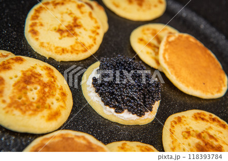 Blinis with black caviar and cream cheese, on a festive dish, mini pancakes, an elegant appetizer Blinis with black caviar and cream cheese, on a festive dish, mini pancakes, an elegant appetizer 118393784