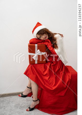 Waiting for a miracle, a woman holds a gift that fills the winter holidays with magic and mystery during the celebration of the new year and Christmas. At Santa's cospac, a woman sits down and sits 118394237