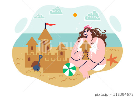 Little girl builds sand castle sitting on sea beach, enjoying trip to resort during holidays 118394675