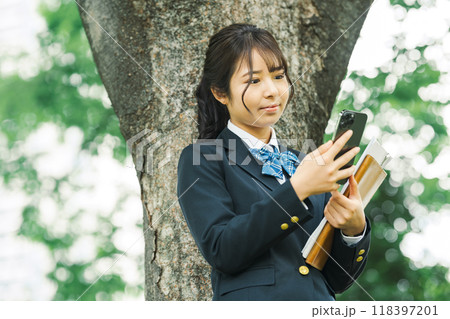 木陰でスマホを見る女子高校生 木陰でスマホを見る女子高校生 118397201