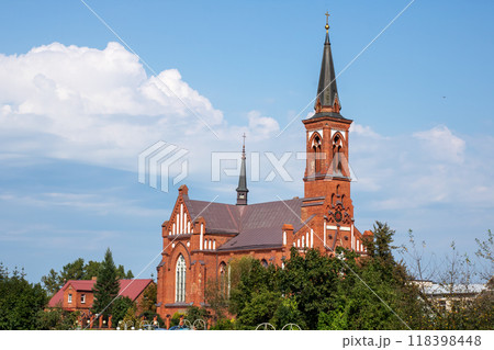A large red brick church building with an elegant steeple surrounded by trees A large red brick church building with an elegant steeple surrounded by trees 118398448