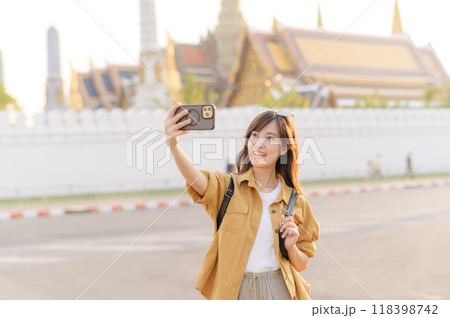 Traveler asian woman in her 30s explores the Grand Palace with a local guide. Uncover hidden gems and immerse yourself in Thai culture with her adventure. 118398742