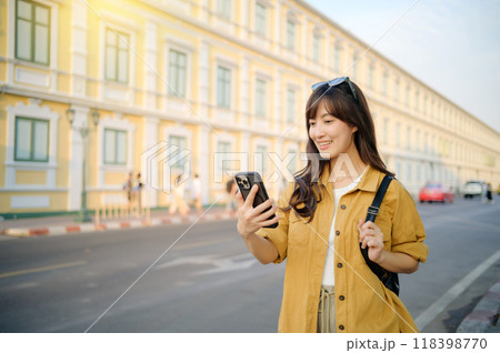 Traveler asian woman in her 30s using smartphone for navigation destination on the urban street at Bangkok, Thailand. Traveler asian woman in her 30s using smartphone for navigation destination on the urban street at Bangkok, Thailand. 118398770