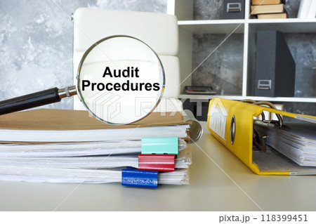 Magnifying glass with audit procedures text on documents. Financial scrutiny. 118399451