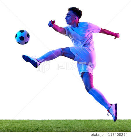 Focused football player, in vibrant neon light during training session, works on controlling ball in air, demonstrating athleticism. Focused football player, in vibrant neon light during training session, works on controlling ball in air, demonstrating athleticism. 118400234