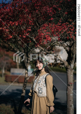 Seasonal delight, Asian woman in casual dress enjoys a holiday in Japan, amid vibrant foliage, a charming lake, and the beauty of Kyoto's fall scenery. 118400962