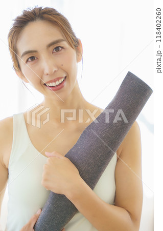オンラインヨガサロンの準備でマットを敷く若い女性 オンラインヨガサロンの準備でマットを敷く若い女性 118402260