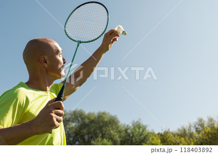 Man playing badminton on green sport court in public park. Outdoors. Summer sports game. Copy space. Close up. 118403892