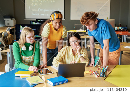 Group of young people collaborating on software with young woman as female teacher at IT class in school or college 118404210