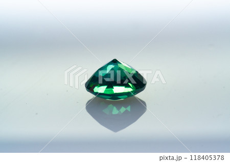 Radiant Green Gemstone with Faceted Sparkle Reflecting Elegant Light on Smooth Surface Radiant Green Gemstone with Faceted Sparkle Reflecting Elegant Light on Smooth Surface 118405378