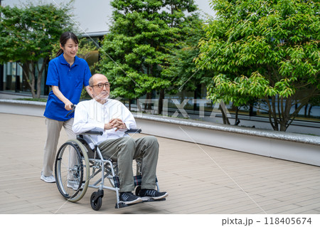 車いすのシニア男性と介護施設スタッフ 118405674